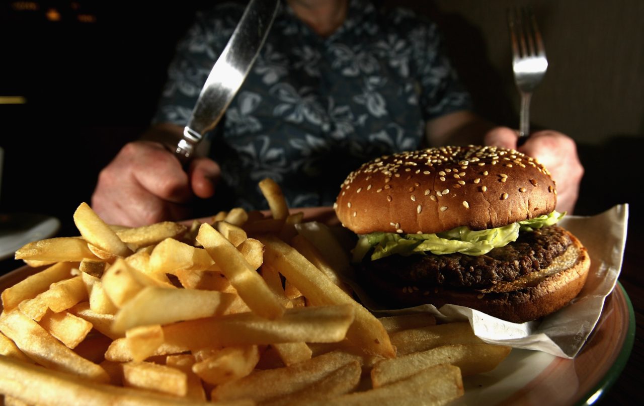GLASGOW, UNITED KINGDOM - JUNE 07: In this photo illustration a man eats a hamburger ind chips in a cafe on June 7,2006 in Glasgow, Scotland. New figures are suggesting that a large proportion of the population is clinically obese.