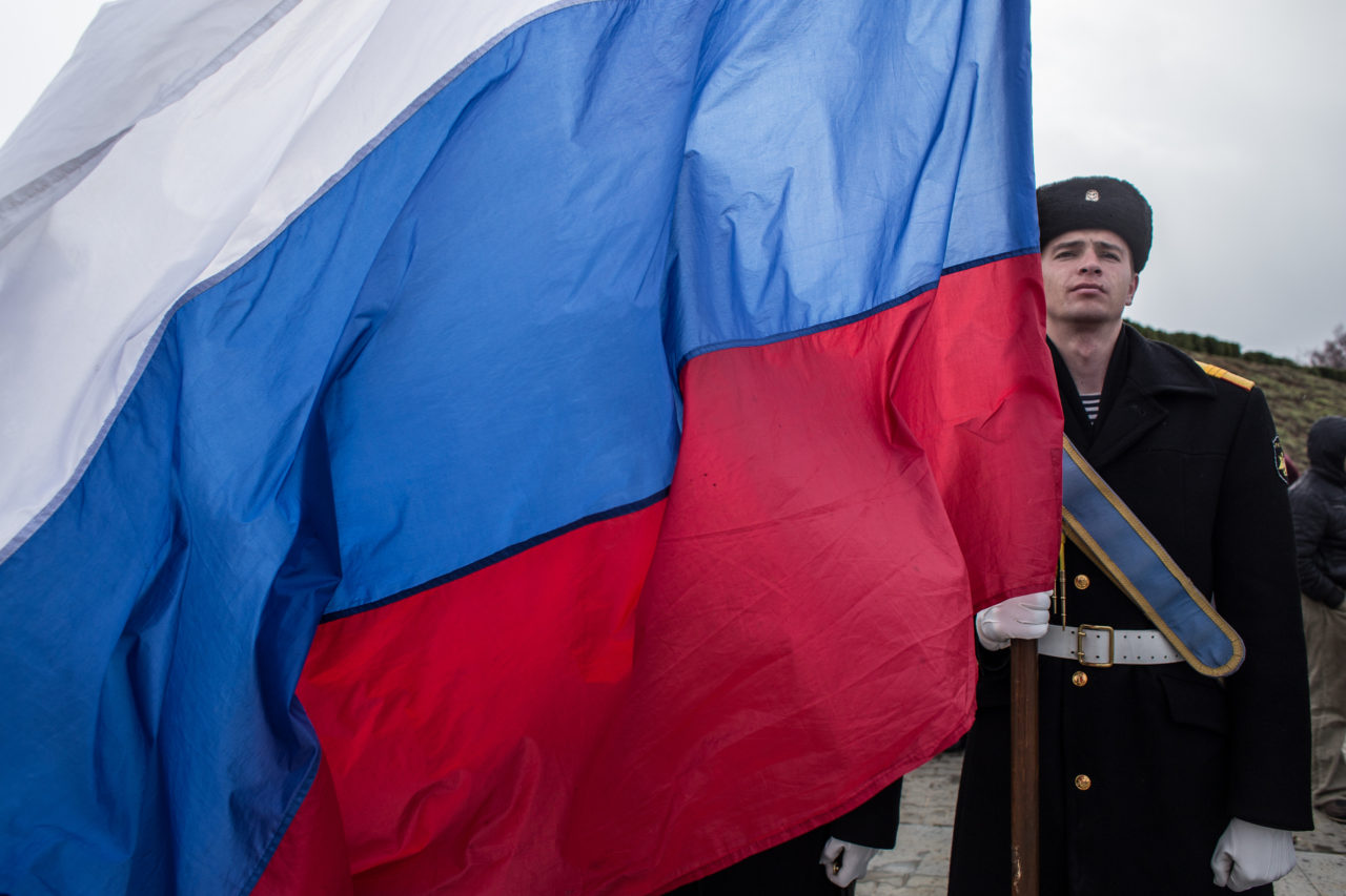SEVASTOPOL, CRIMEA - MARCH 18: A Navy sailor holds a Russian flag as people celebrate the first anniversary of the signing of the decree on the annexation of the Crimea by the Russian Federation, on March 18, 2015 in Sevastopol, Crimea. Crimea, an internationally recognised Ukrainian territory with special status, was annexed by the Russian Federation on March 18, 2014. The annexation, which has been widely condemned, took place in the aftermath of the Ukranian revolution.